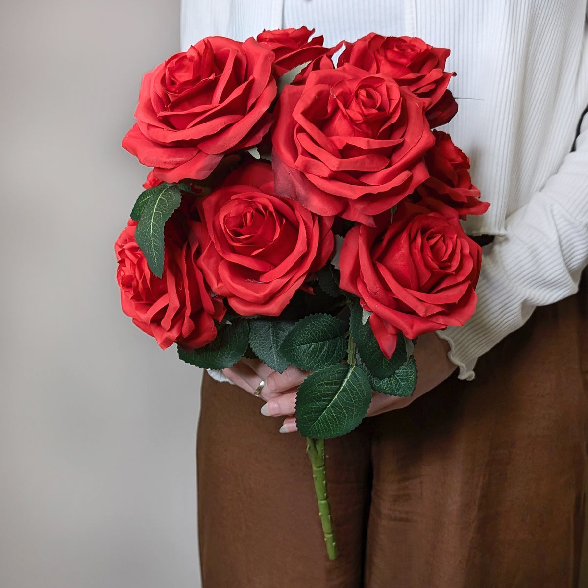 Roter Seidenrosenstrauß mit 10 Blüten in Hand gehalten, frontal