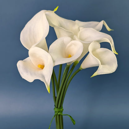 Sieben weiße Calla-Seidenblumen als Bund vor blauem Hintergrund