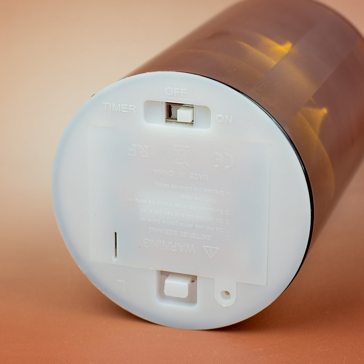 Detailaufnahme der Unterseite der Leonardo LED-Glaskerze mit Ein/Aus/Timer-Schalter und Batteriefach für drei AA-Batterien.