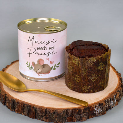 Dosenkuchen „Mausi mach mal Pausi“ mit rosa Maus-Motiv neben ausgepacktem Schokoladen-Brownie auf Holzscheibe