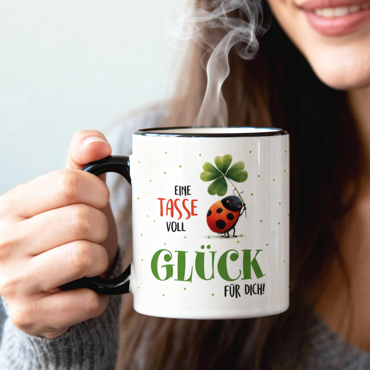 Glücksbringer Tasse mit Kleeblatt und Marienkäfer in der Hand gehalten