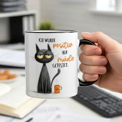 Lustige Tasse mit Spruch „Ich wurde positiv auf müde getestet“ in der Hand