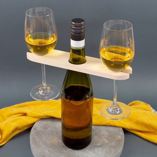 Weinbutler auf einer Weinflasche mit zwei seitlich eingehängten Weingläsern und gelbem Tuch im Hintergrund