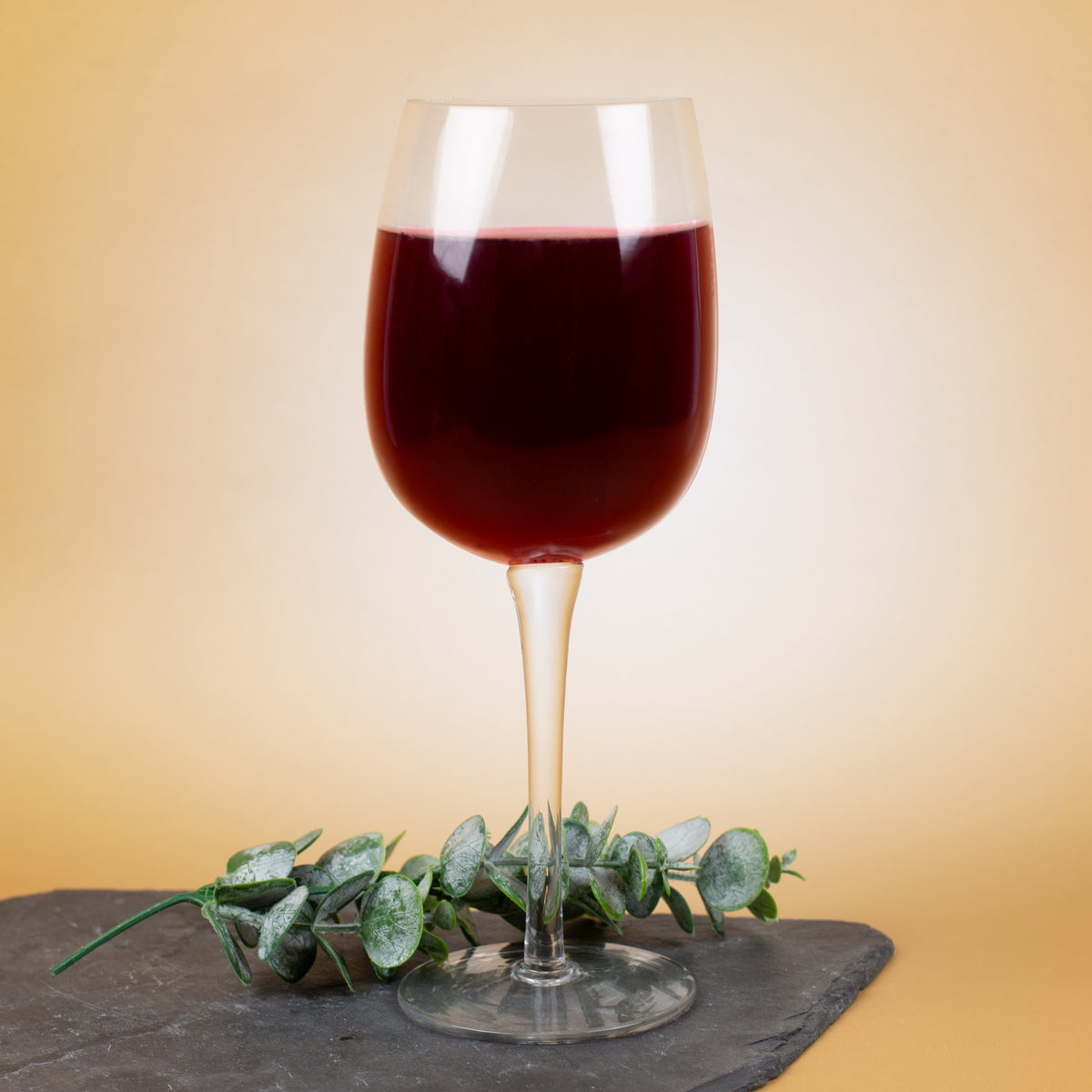 Halbes Weinglas aus Glas als Gag-Geschenk, gefüllt mit dunklem Rotwein, Fokus auf besondere Glasform