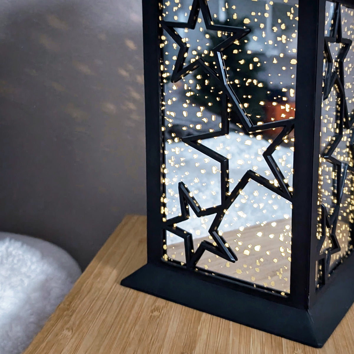 Detailaufnahme der leuchtenden LED-Laterne mit Sternenlichtspiel auf Holztisch