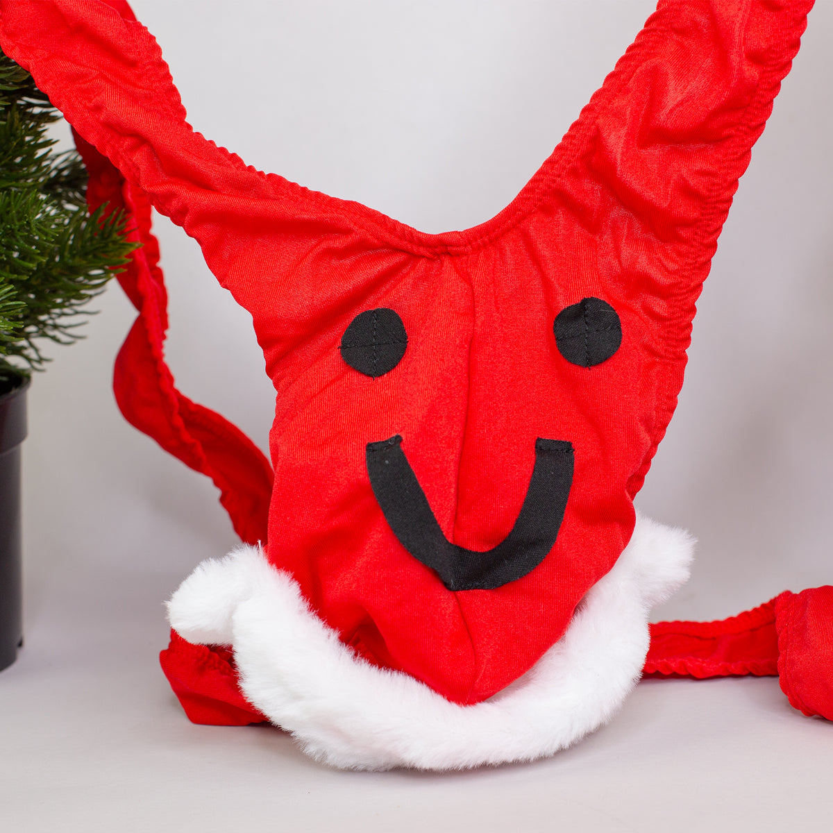 Nahaufnahme des roten Mankinis mit schwarzem Smiley-Gesicht und weißem Pelzbesatz.