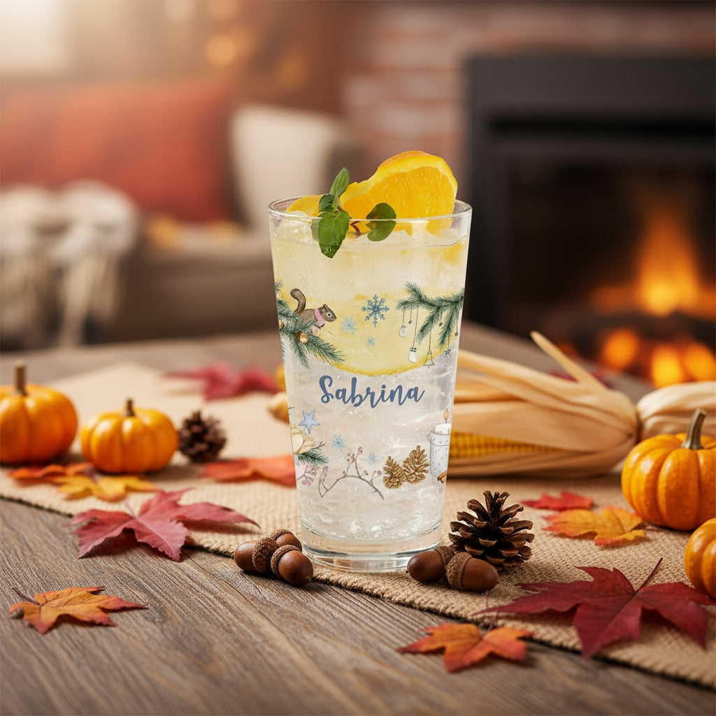 Weihnachts-Trinkglas mit Namensaufdruck „Sabrina“ zwischen Herbstdeko mit Kürbissen und Tannenzapfen