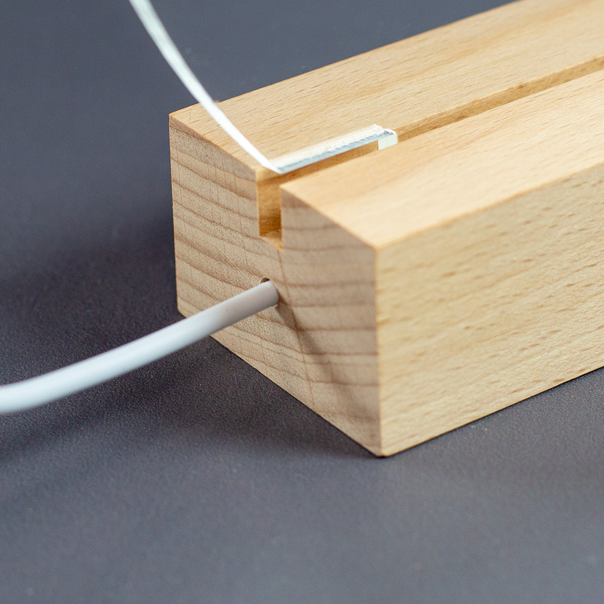 Nahaufnahme des Holzsockels mit dem USB-C-Kabel.