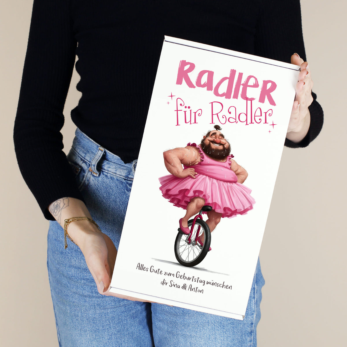 Geschenkbox „Radler für Radler“ mit witzigem Motiv eines Mannes im pinken Tutu, gehalten in der Hand