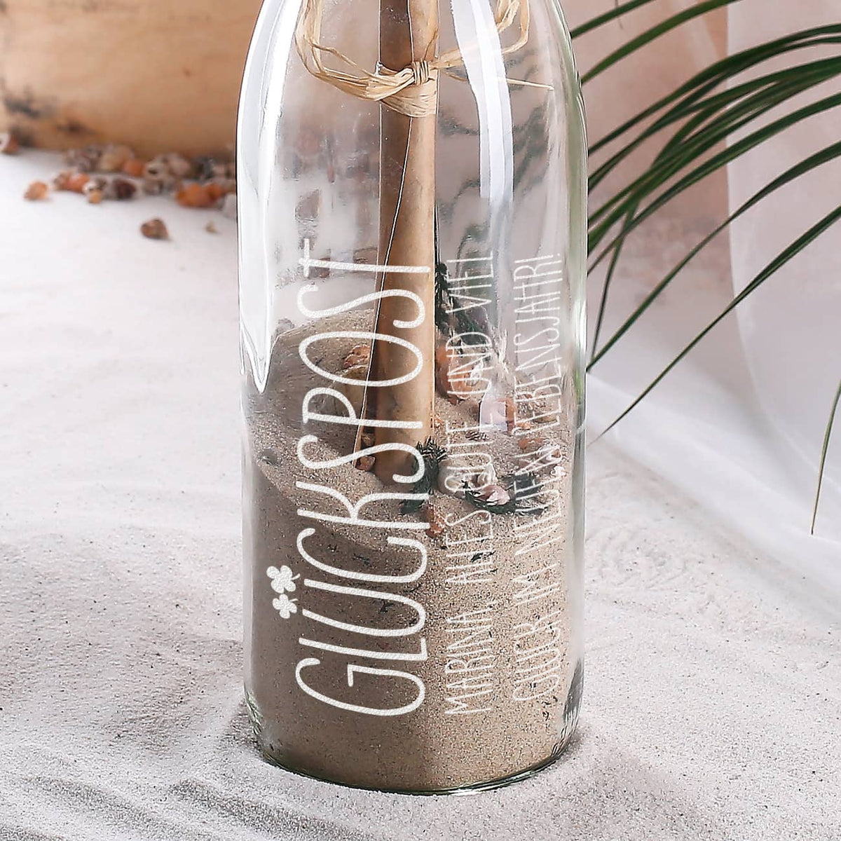 Flaschenpost mit Sand, Muscheln und marmoriertem Papier