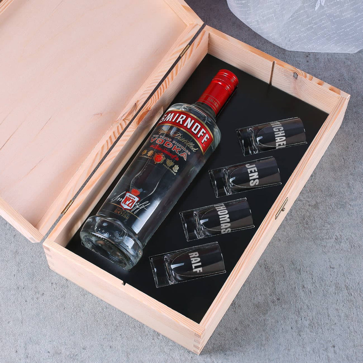 4 gravierte Vodka-Gläser und eine Flasche Smirnoff-Vodka haben im Inneren der Holzkiste platz.