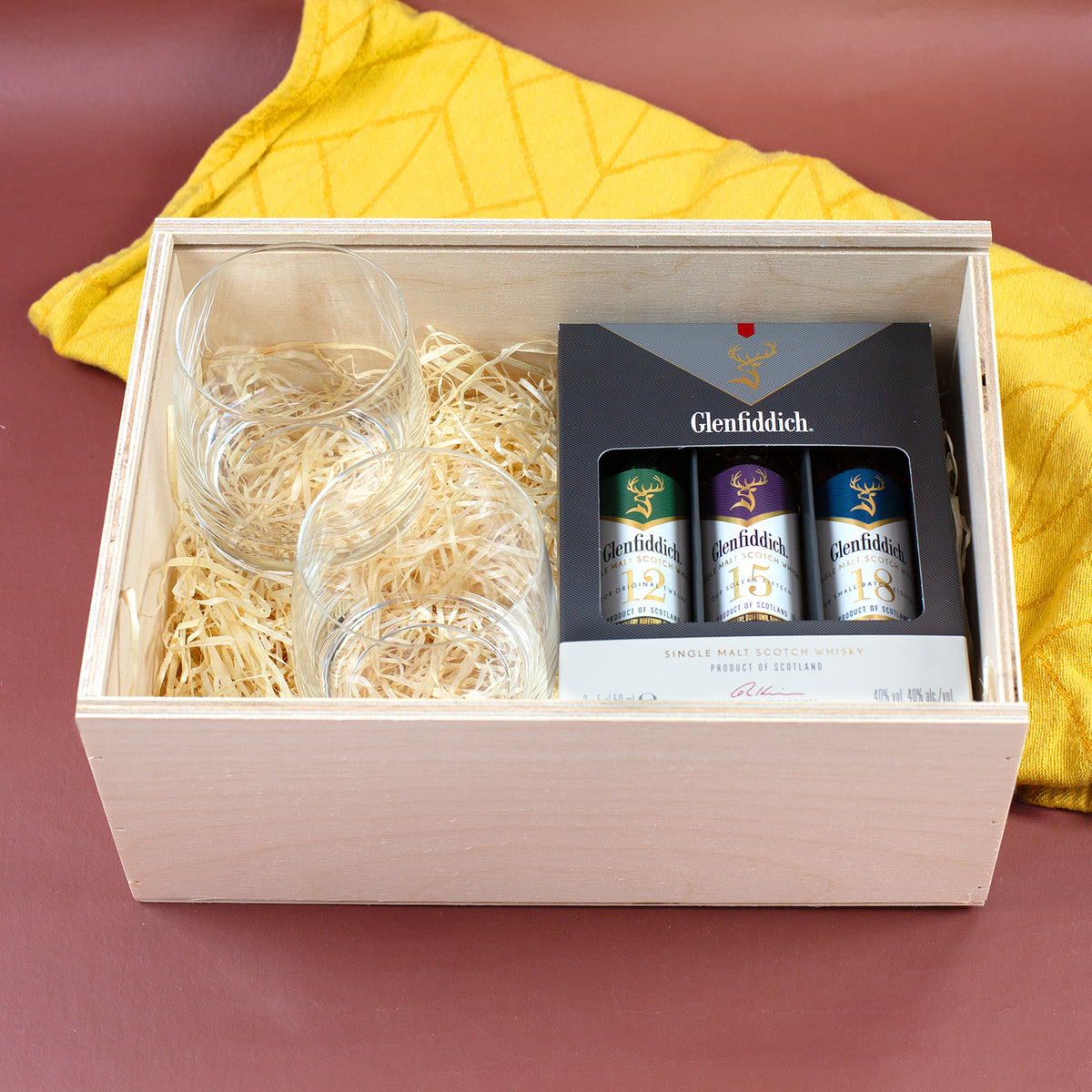 Geöffnete Holzbox für personalisiertes Whisky-Geschenkset mit Whiskygläsern, Holzwolle und Glenfiddich Tasting Set
