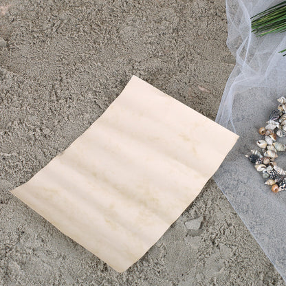Leeres Pergamentpapier als Nachricht für Flaschenpost, dekoriert auf Sand mit Muscheln und Netz