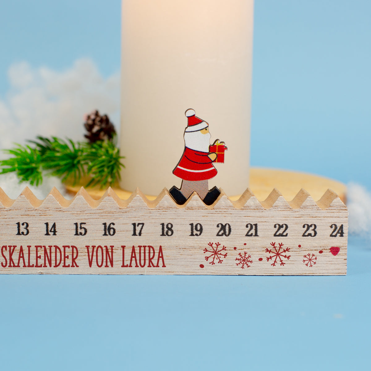 Weihnachtsdeko: Personalisierter Holz-Adventskalender mit Santa-Figur, Schneeflocken und Kerze als Hintergrund.