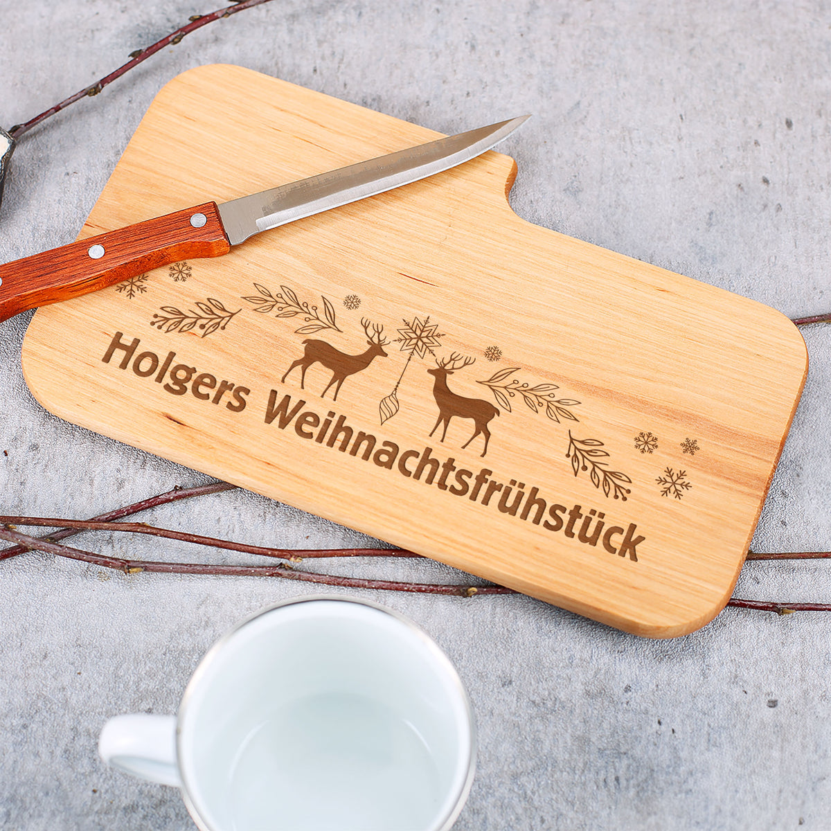 Personalisiertes Brettchen mit Gravur „Holgers Weihnachtsfrühstück“, Messer und Tasse im Hintergrund