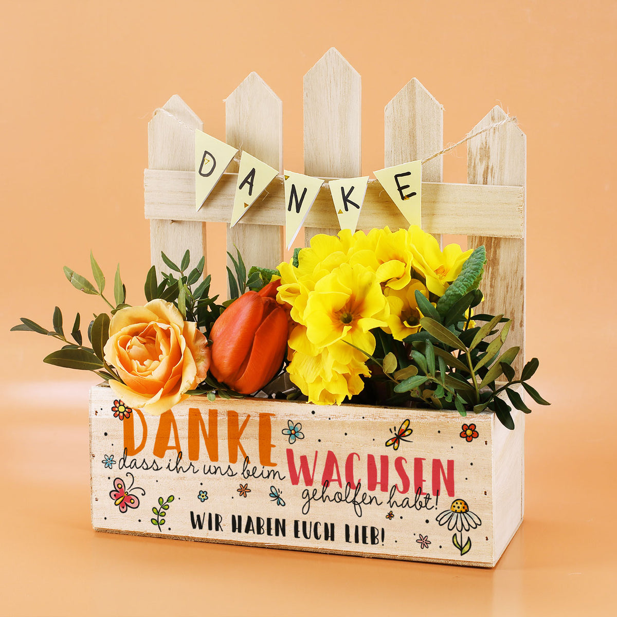 Pflanzkiste mit Zaun und Blumen, Text „Danke, dass ihr uns beim Wachsen geholfen habt“ und Wunschtext „Wir haben euch lieb!“