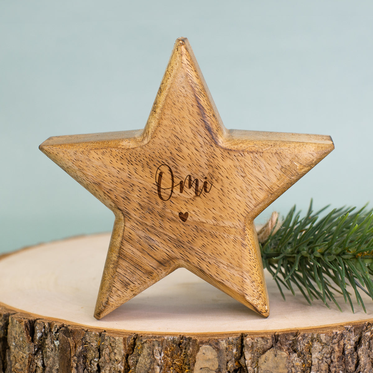 Holzstern mit Gravur „Omi“ als Weihnachtsdekoration auf einem Holztablett mit Tannenzweig