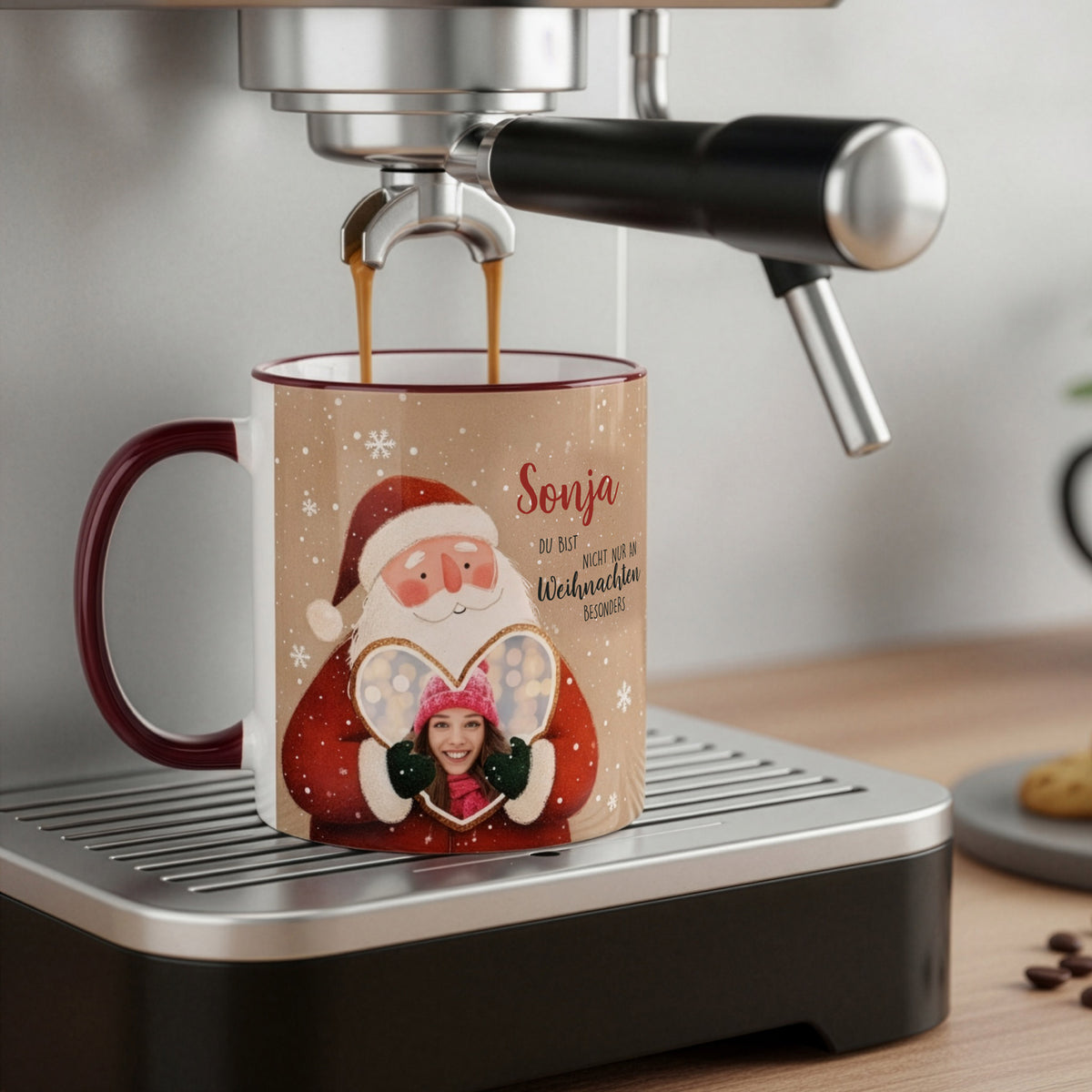 Personalisierte Weihnachtstasse mit Weihnachtsmann und Lebkuchenherz mit Foto, steht unter einer Kaffeemaschine beim Befüllen