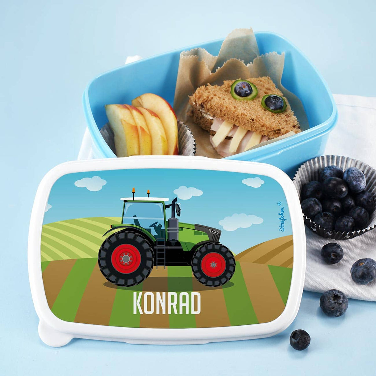 Blaue Brotdose mit Name und Traktor auf Deckel
