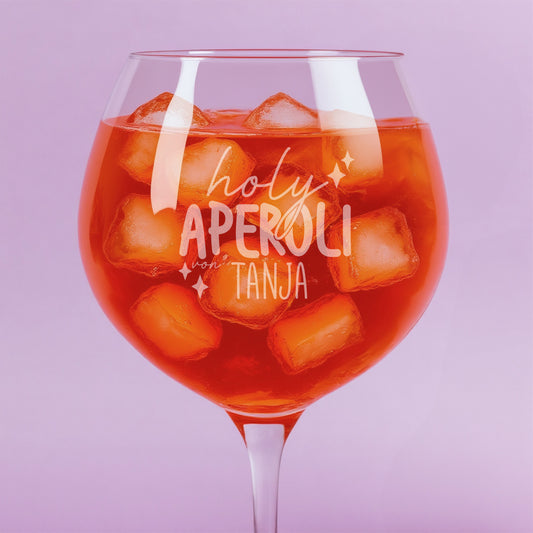 Nahaufnahme der Gravur „holy aperoli von Tanja“ auf gefülltem Weinglas mit Eiswürfeln – feine Lasergravur mit verspieltem Schriftzug und Sternmotiven.