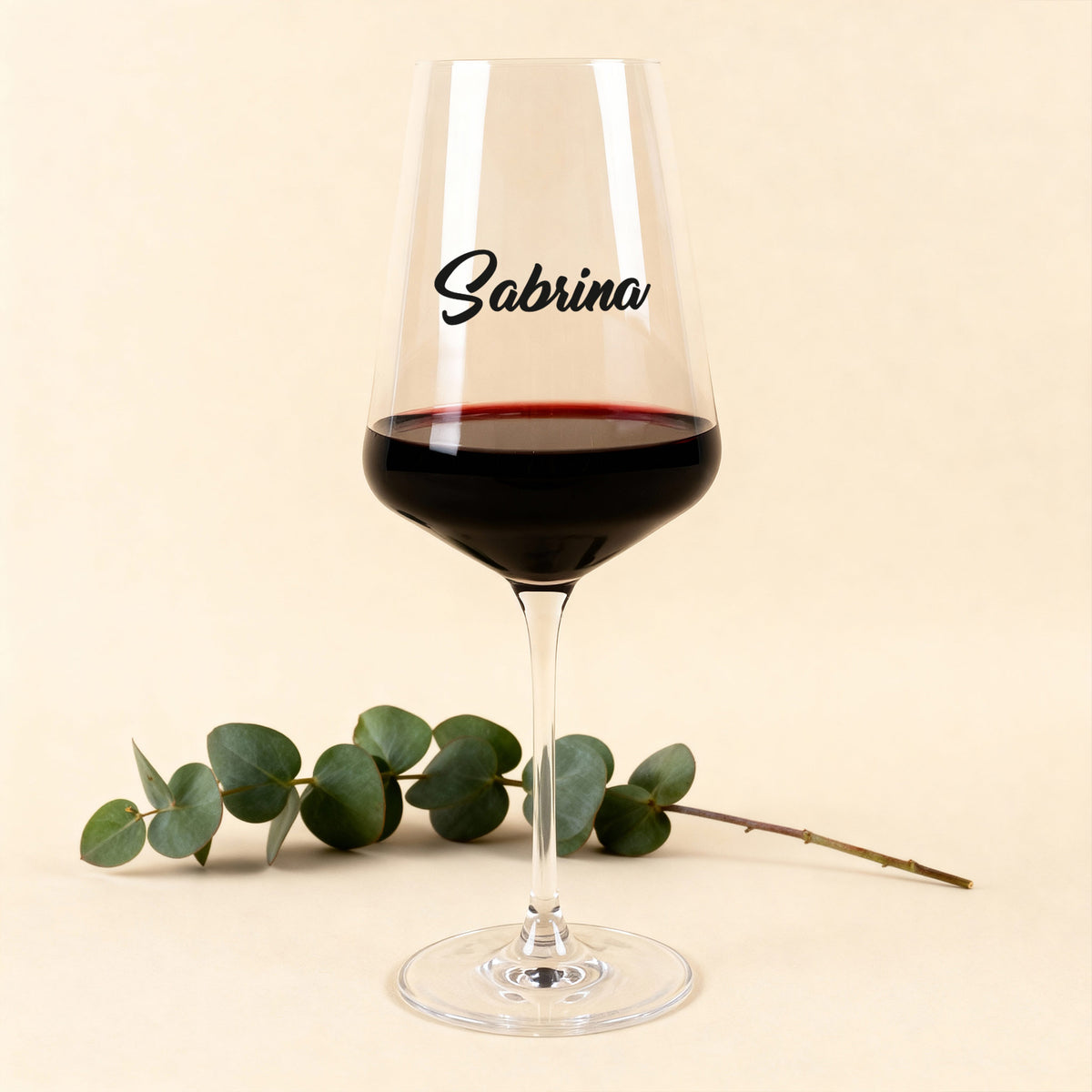 Leonardo Weinglas Puccini mit schwarzem Namensdruck, gefüllt mit Rotwein, vor hellem Hintergrund