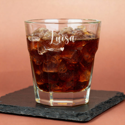 Leonardo-Trinkglas mit Gravur eines Namens und Herzsymbols, gefüllt mit Cola und Eiswürfeln, auf Schieferunterlage – modernes personalisiertes Glas mit emotionalem Detail.