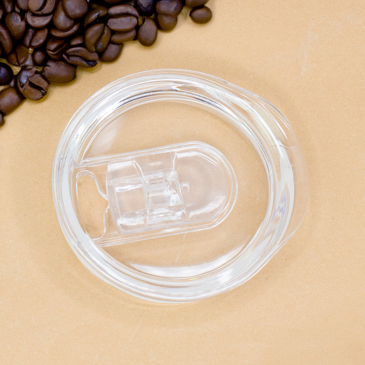 Transparenter Deckel des Thermobechers einzeln auf heller Unterlage mit Kaffeebohnen daneben