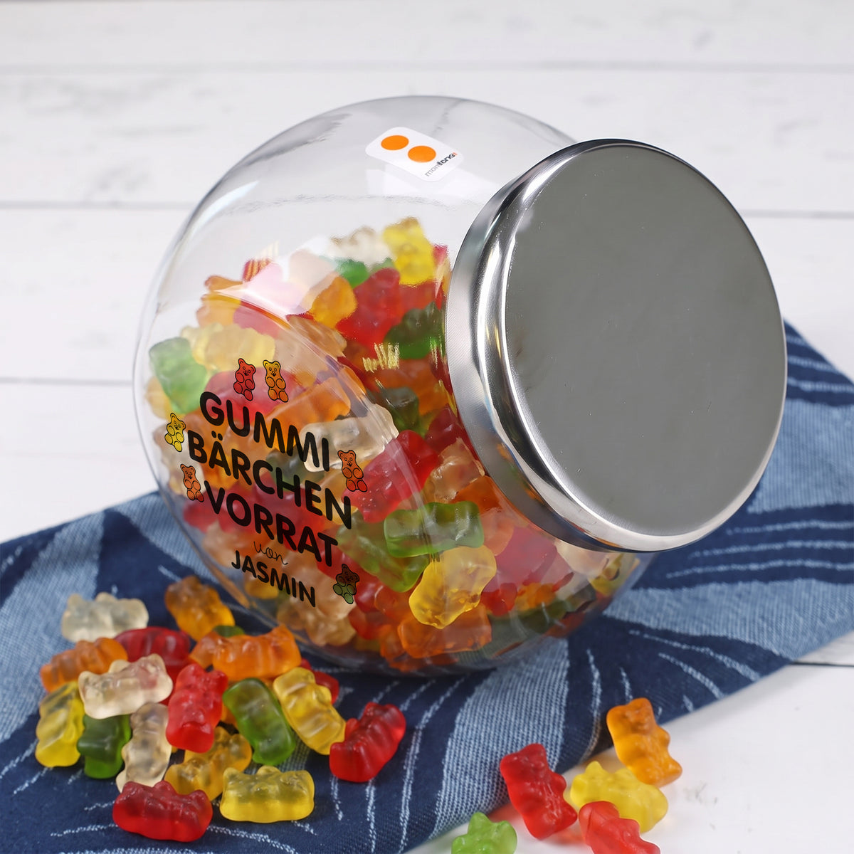 Mit Gummibärchen gefülltes personalisiertes Vorratsglas „von Jasmin“ mit silberfarbenem Metalldeckel und Süßigkeiten davor