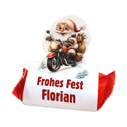 Freigestellter Mini-Stollen mit Geschenkverpackung „Frohe Weihnachten Maximilian“ und Weihnachtsmann auf Motorrad