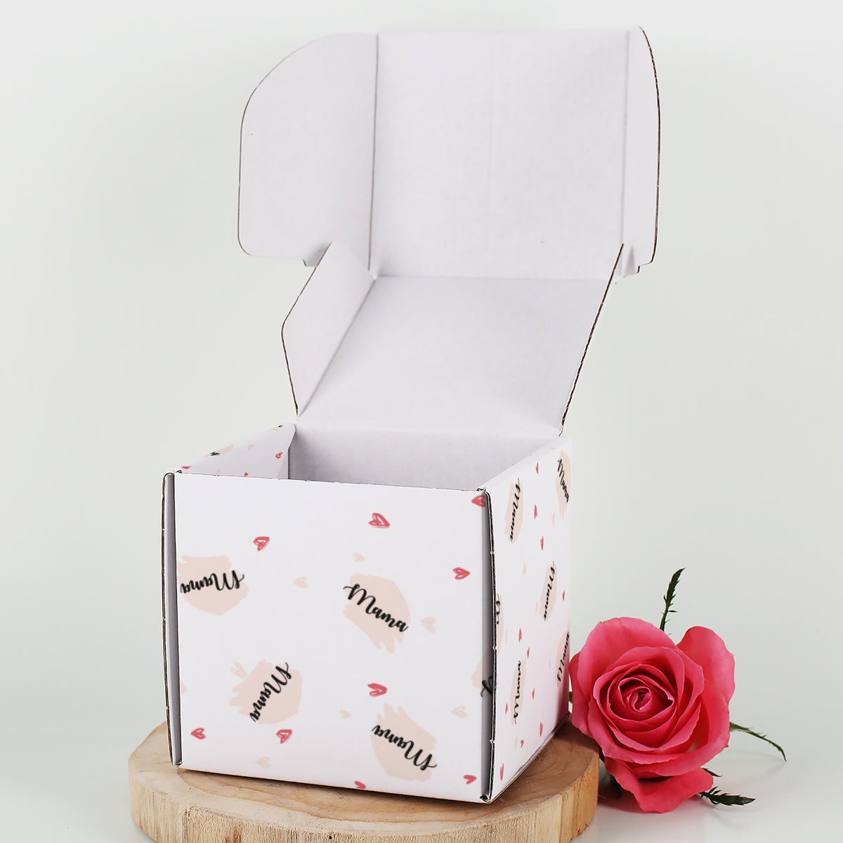 Geschenkbox mit Herz-Motiv personalisiert mit Name & Wunschtext geöffnet neben einer Rose dargestellt.