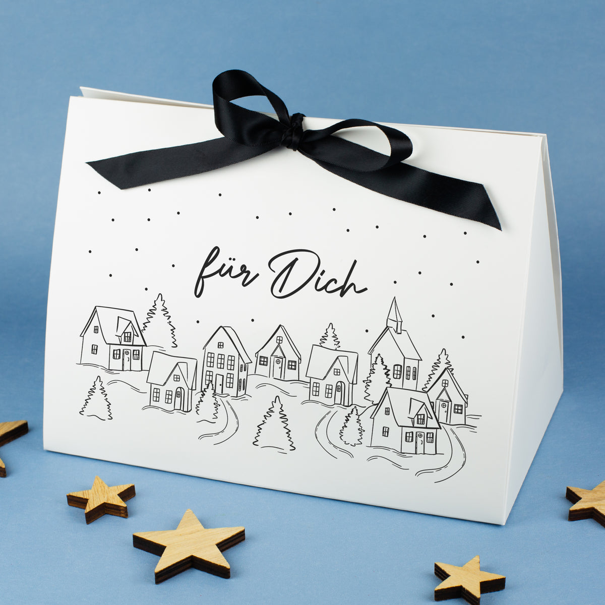 Sehr große Geschenktasche mit Winterdorf-Motiv und personalisiertem Text „für Dich“, auf blauem Hintergrund mit Holzsternen arrangiert.