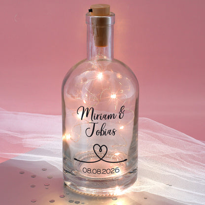 Bedruckte Glaskaraffe mit LED-Lichterkette vor rosa Hintergrund