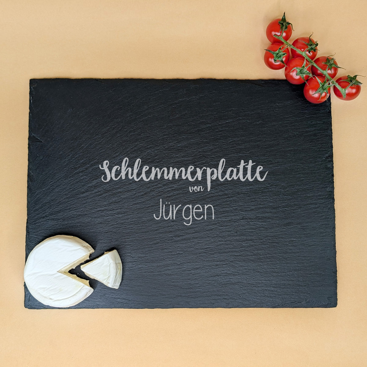 Schieferplatte mit Gravur „Schlemmerplatte von Jürgen“, dekoriert mit Camembert und Tomaten