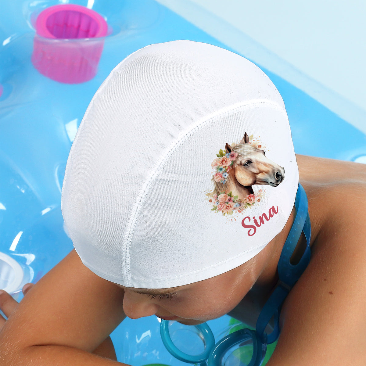 Kind mit Badekappe Pferd und Name „Sina“ im Wasser