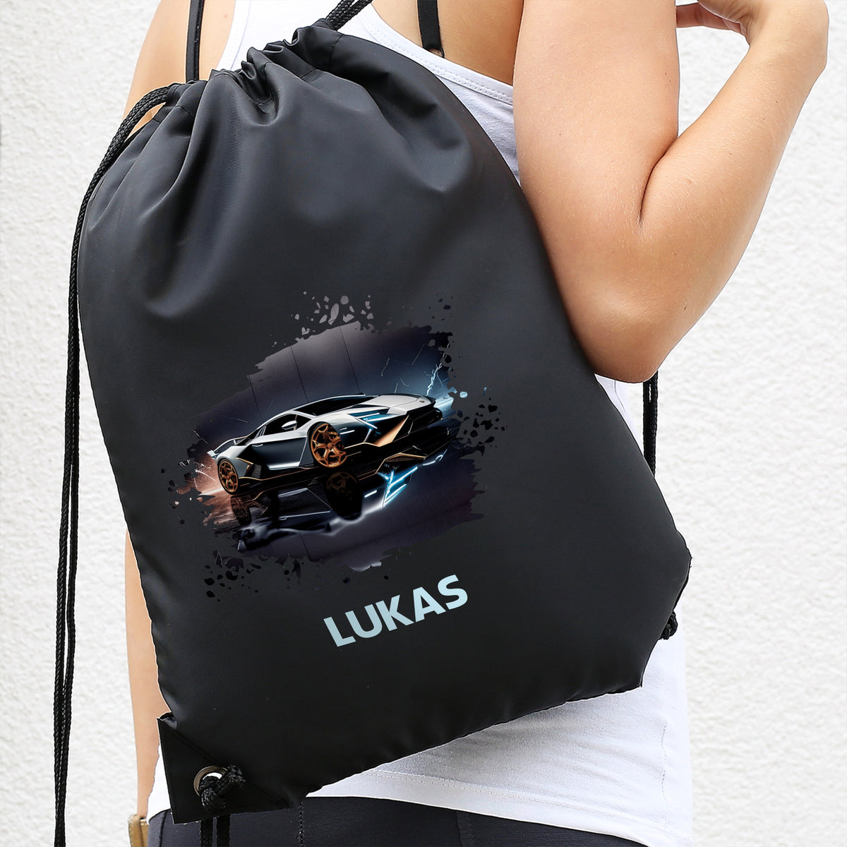 Schwarzer Turnbeutel mit Sportwagen-Design und Name „Lukas“, getragen auf dem Rücken