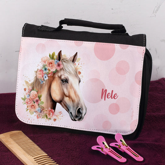 Schwarze Waschtasche mit rosa Pferdemotiv und Name „Nele“ auf Handtuch mit Kamm und Haarclips