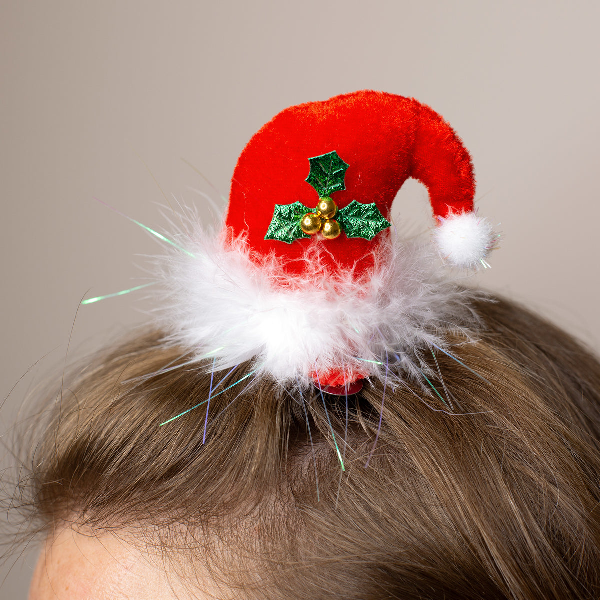 Weihnachtlicher Haarclip in Form einer roten Plüschmütze mit Flaum, getragen im Haar als festliches Accessoire.