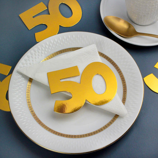 Jumbo-Konfetti Zahl 50 in Gold auf weißem Teller mit Serviette zur Goldenen Hochzeit