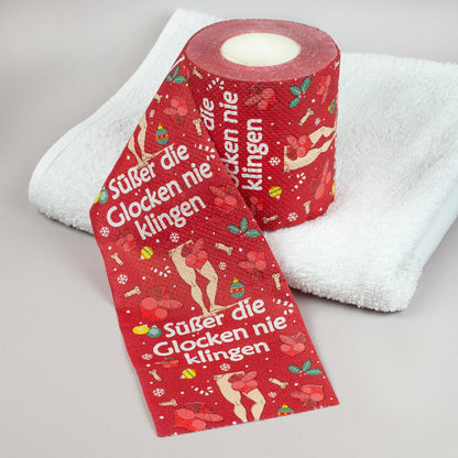 Rote Toilettenpapierrolle mit Weihnachtsmotiv und Spruch „Süßer die Glocken nie klingen“ auf weißem Handtuch